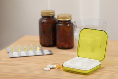 Plastic pill box with different medicament on wooden table