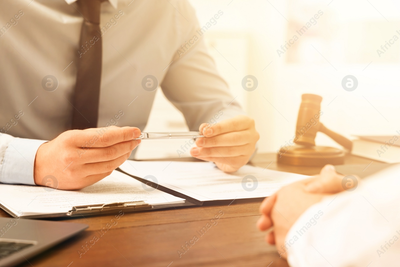 Image of Lawyer working with client at wooden table in office, closeup