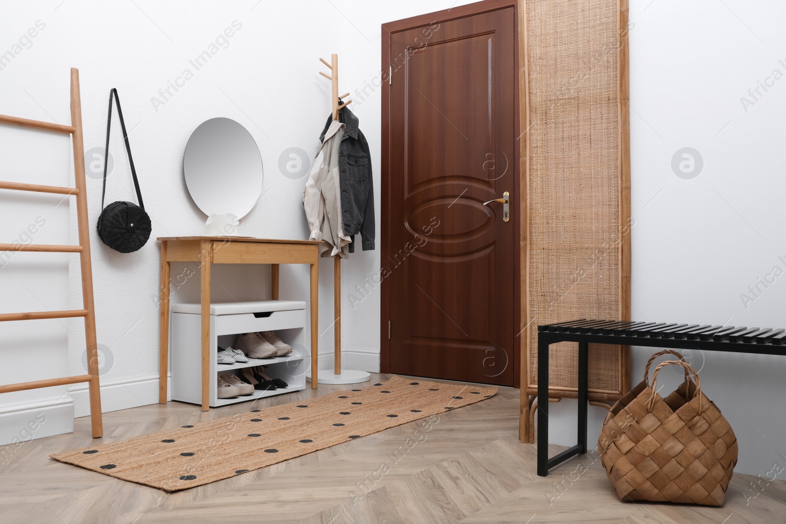 Photo of Shelving unit with shoes and accessories near white wall in hall