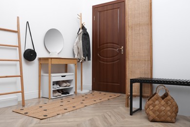 Photo of Shelving unit with shoes and accessories near white wall in hall