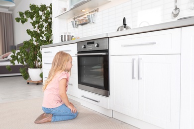 Little girl baking something in oven at home