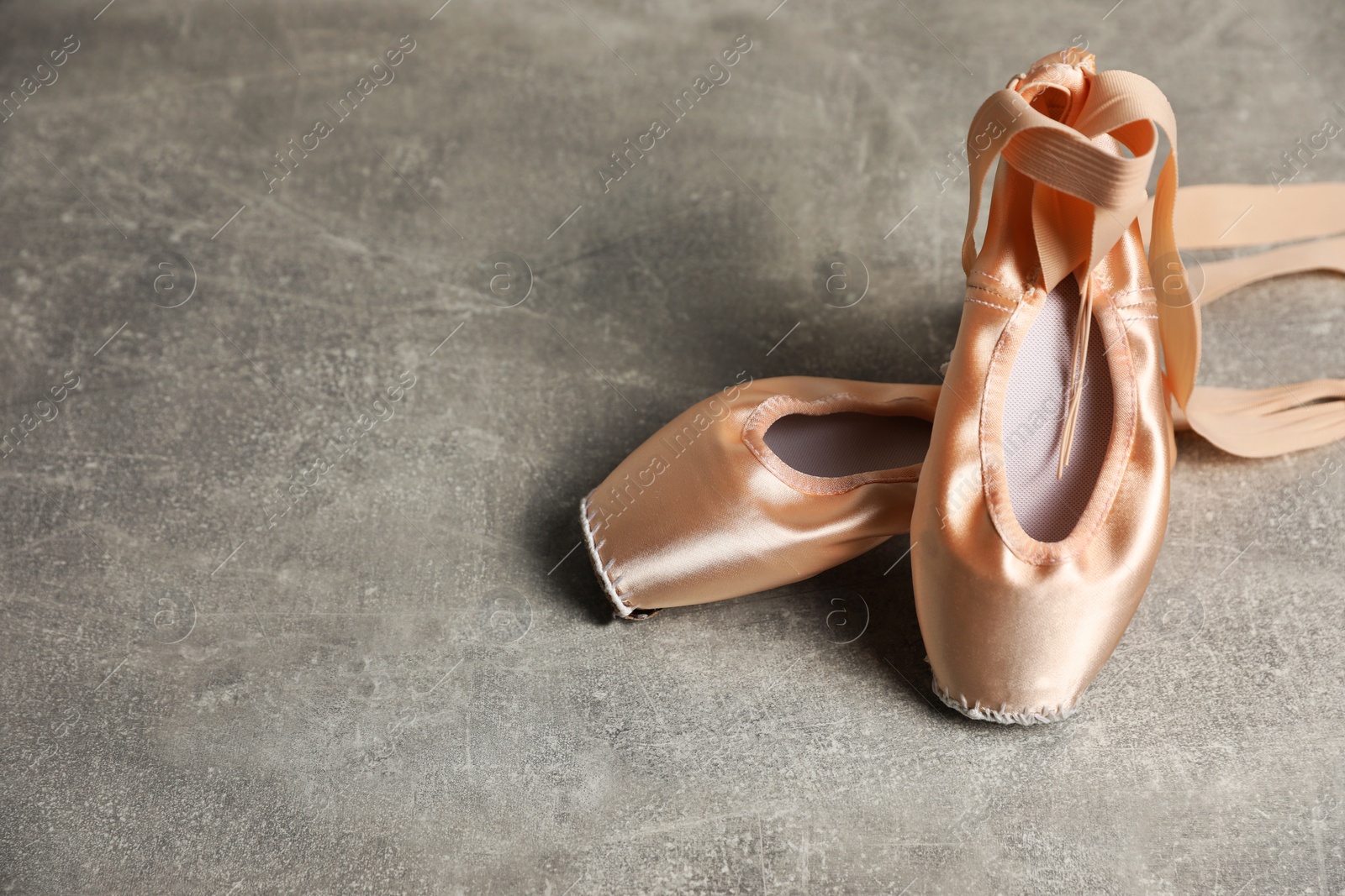 Photo of Ballet shoes. Elegant pointes on grey textured background, space for text