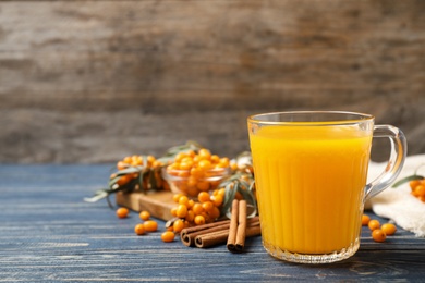 Fresh sea buckthorn tea on blue wooden table. Space for text