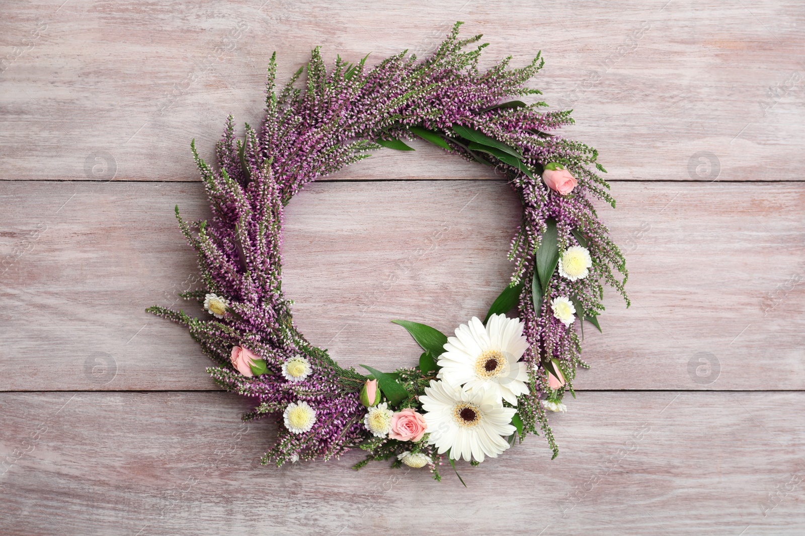 Photo of Beautiful autumnal wreath with heather flowers on light wooden background, top view. Space for text