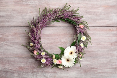 Beautiful autumnal wreath with heather flowers on light wooden background, top view. Space for text