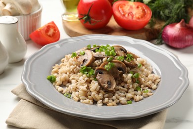 Photo of Delicious pearl barley with onion and mushrooms on white table, closeup