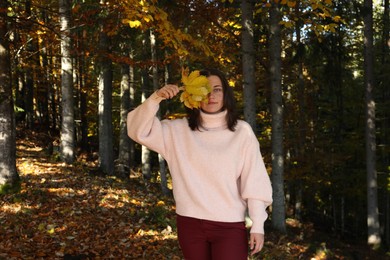 Photo of Portrait of beautiful young woman with autumn leaves in forest