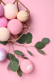 Photo of Bowl with bath bombs and eucalyptus leaves on pink background, flat lay