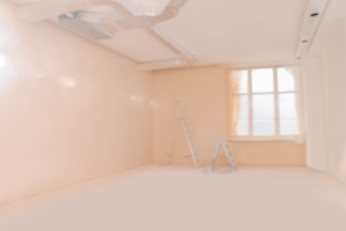 Blurred view of room with pale orange walls and windows prepared for renovation