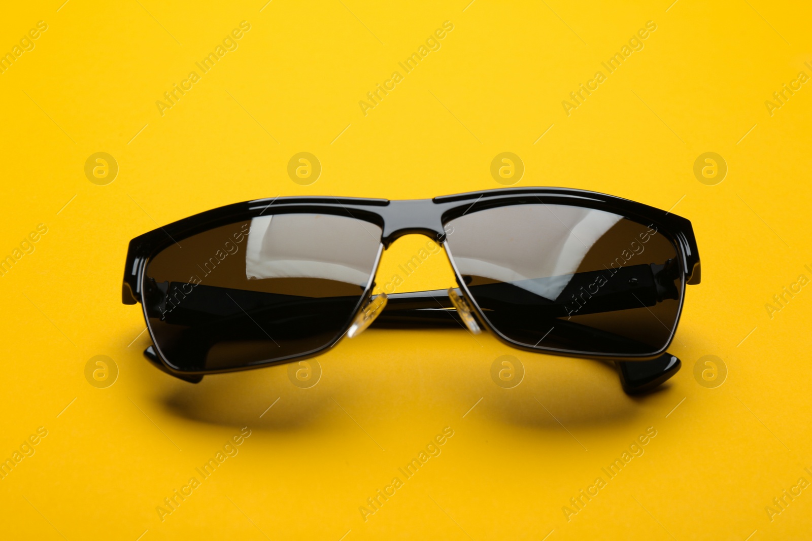 Photo of Stylish sunglasses on yellow background. Fashionable accessory