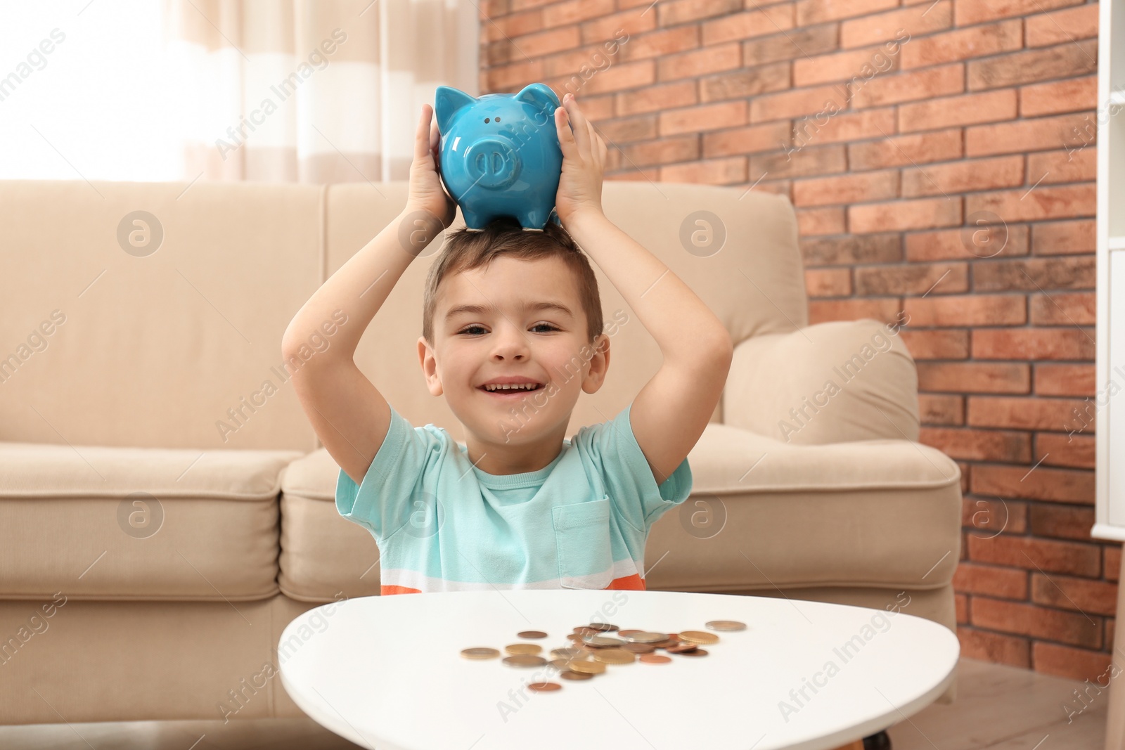 Photo of Little boy with piggy bank and money at home