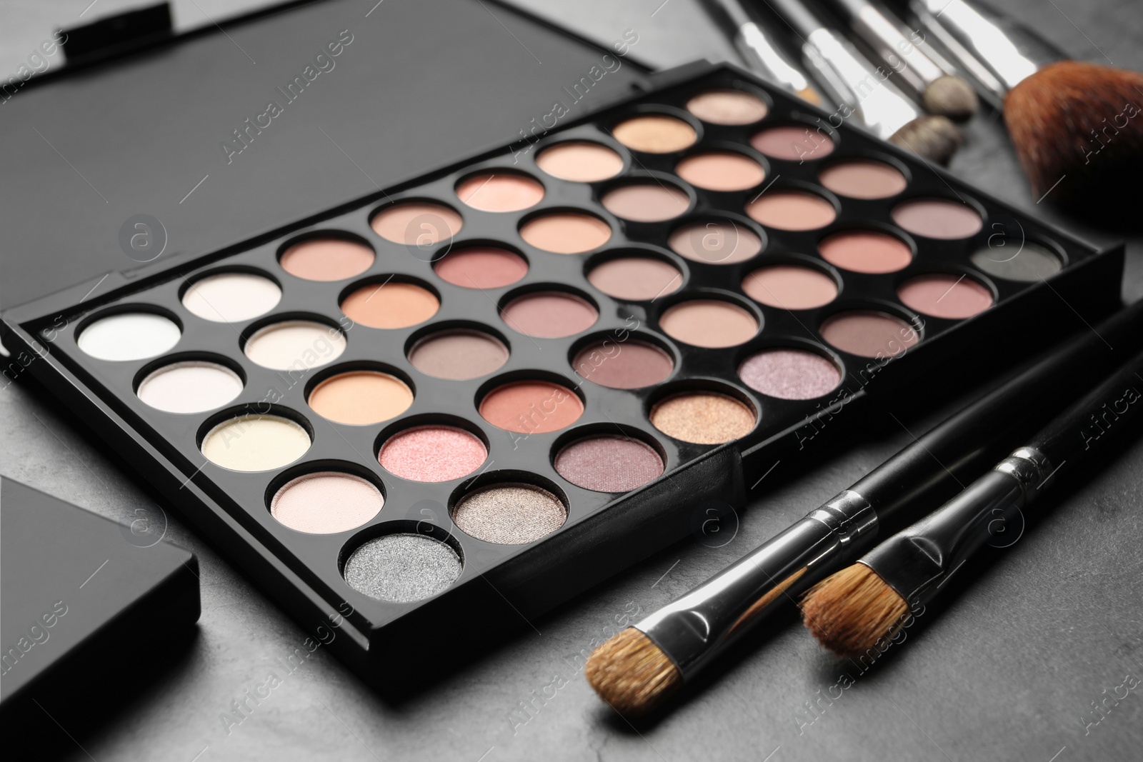 Photo of Beautiful eye shadow palette and brushes on dark grey table