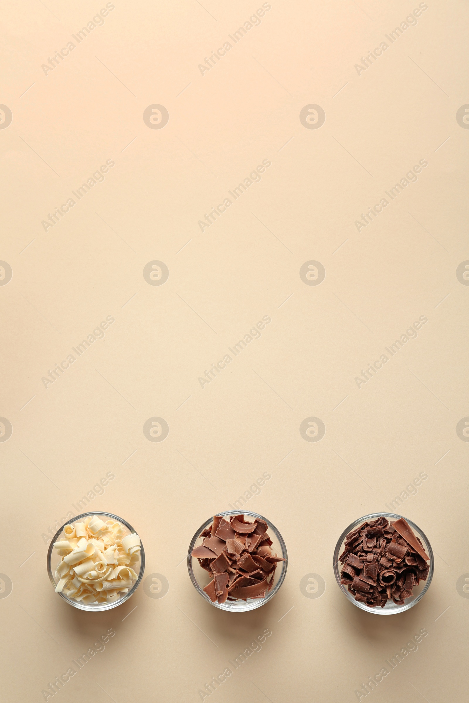 Photo of Bowls with different chocolate curls and space for text on color background, top view