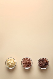 Bowls with different chocolate curls and space for text on color background, top view