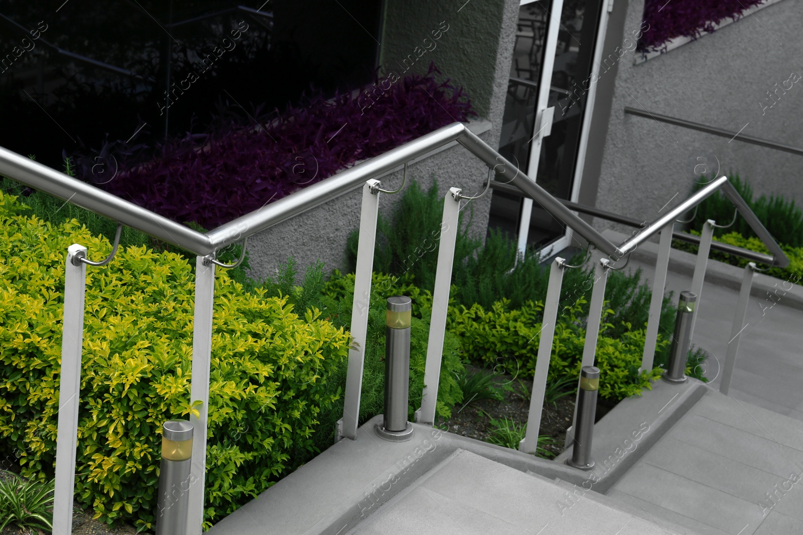 Photo of Outdoor staircase with metal handrails near beautiful plants