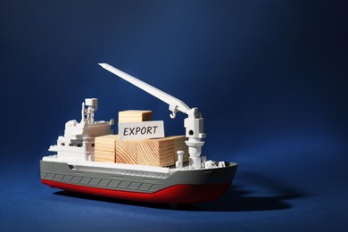 Photo of Toy cargo vessel with wooden cubes on blue background, space for text. Export concept