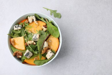 Photo of Tasty salad with persimmon, blue cheese and walnuts served on white table, top view. Space for text