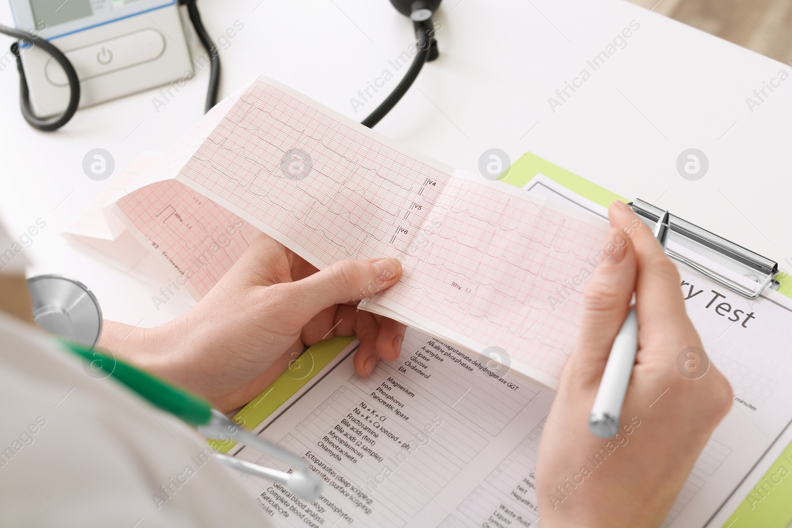 Photo of Doctor examining cardiogram at table in clinic, closeup