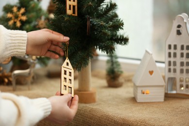 Woman decorating small Christmas tree on window sill indoors, closeup