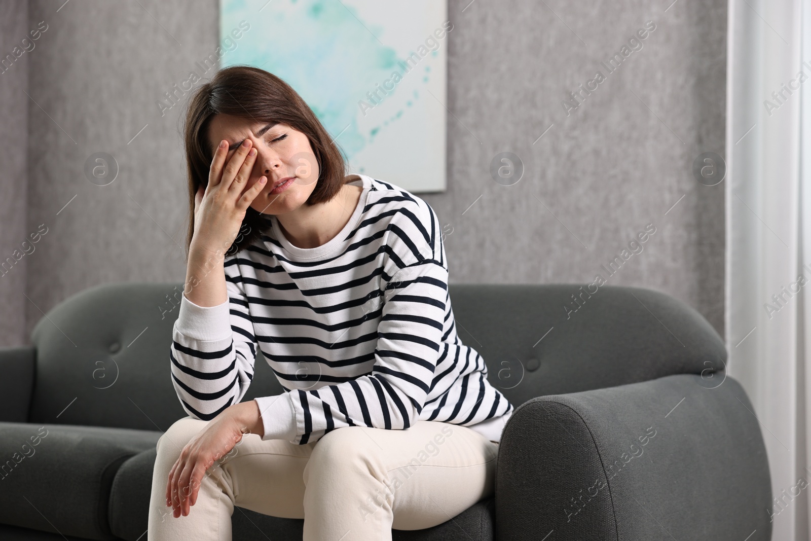 Photo of Overwhelmed woman sitting on sofa at home