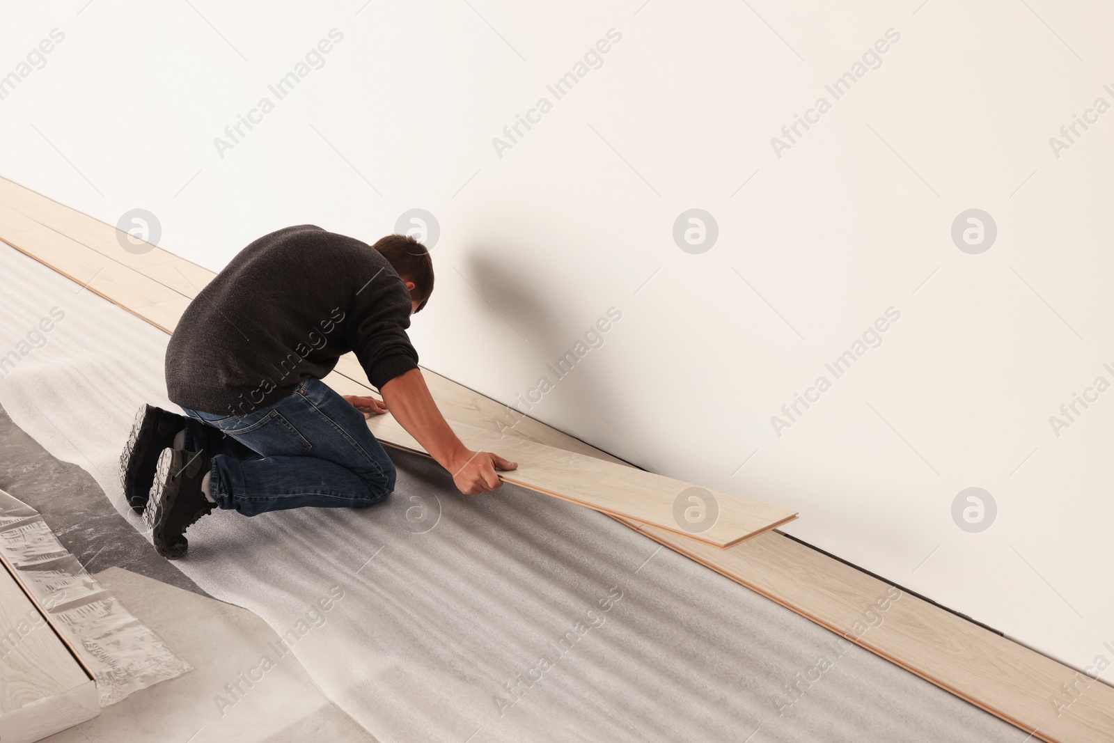 Photo of Professional worker installing new laminate flooring. Space for text