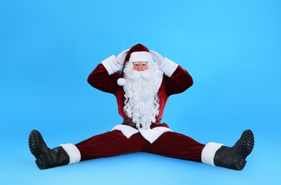 Photo of Funny Santa Claus sitting on light blue background