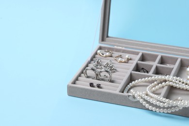 Jewelry box with many different accessories on light blue background, space for text