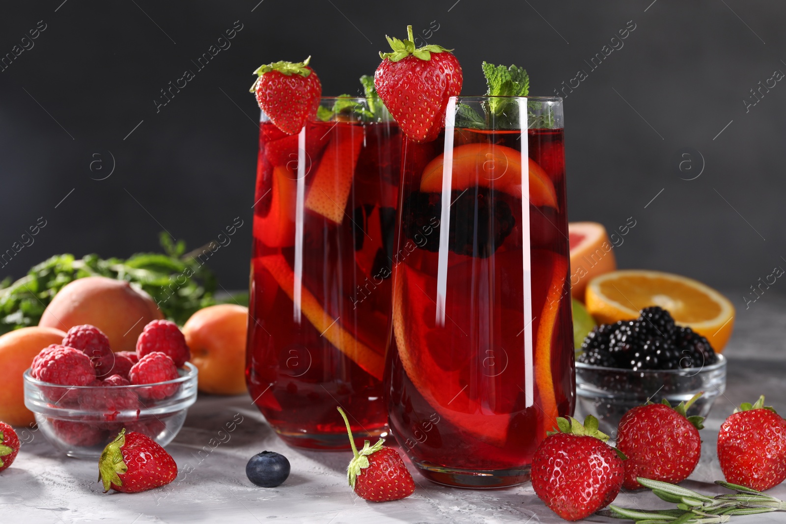 Photo of Delicious refreshing sangria and ingredients on light grey table, closeup