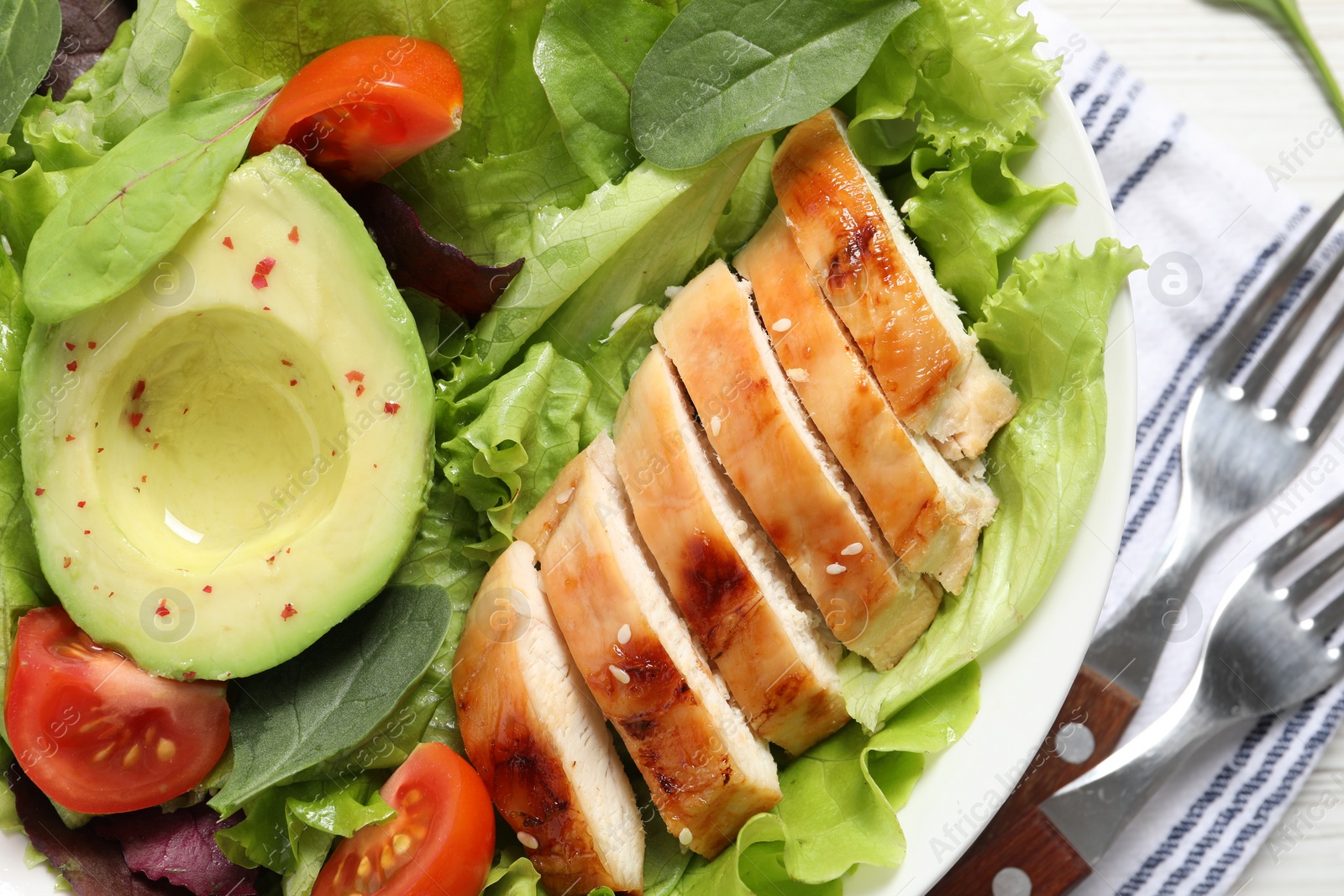 Photo of Delicious salad with chicken, cherry tomato and avocado on table, top view