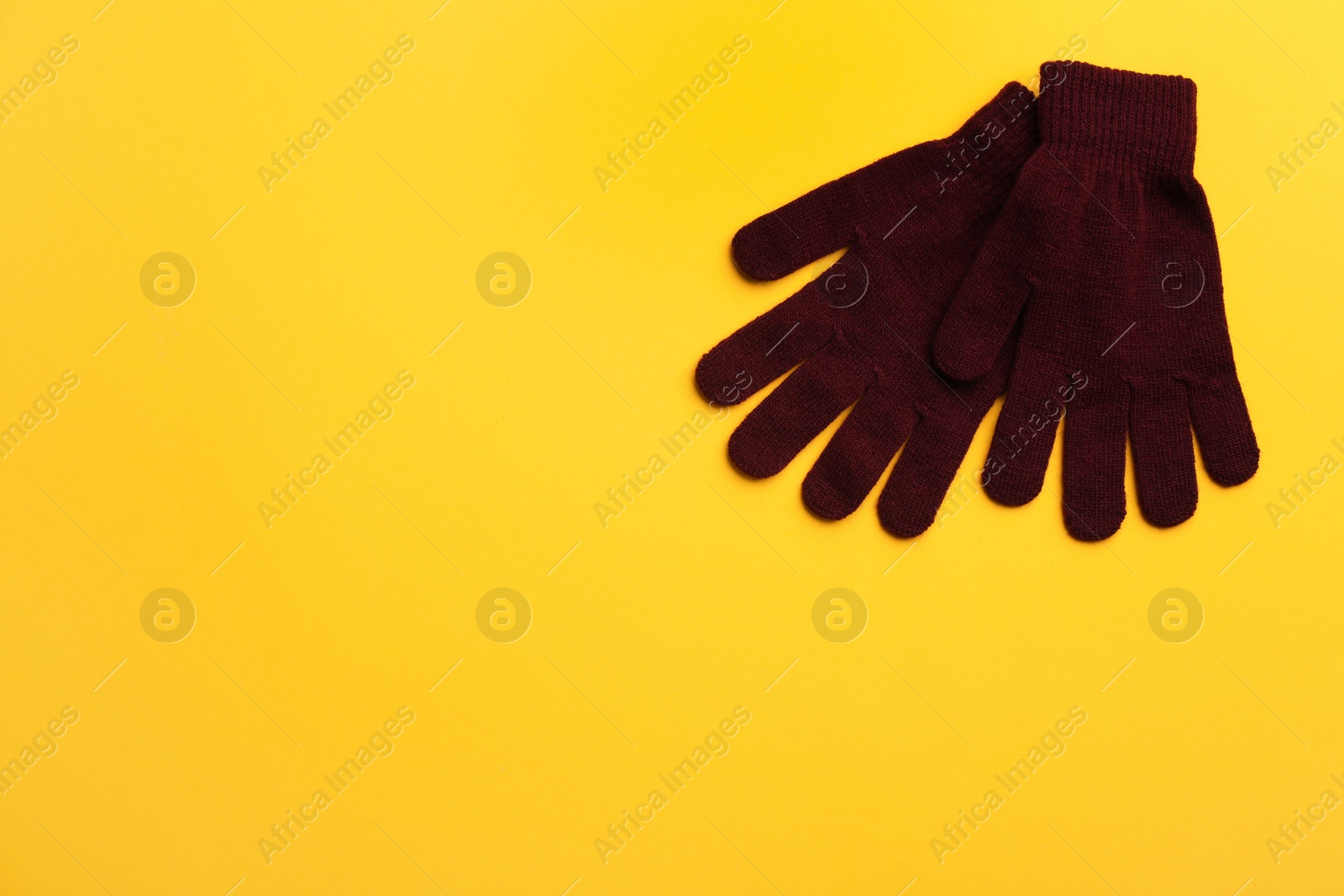 Photo of Pair of stylish woolen gloves on yellow background, flat lay. Space for text