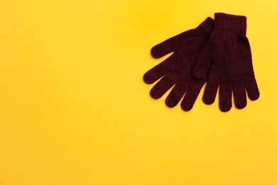 Pair of stylish woolen gloves on yellow background, flat lay. Space for text