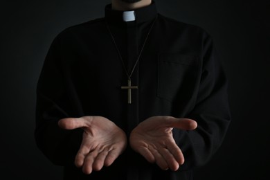 Photo of Priest reaching out his hands on dark background, closeup