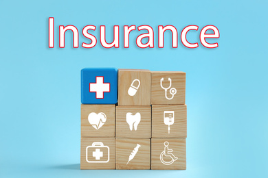 Image of Wooden cubes with icons and word INSURANCE on light blue background