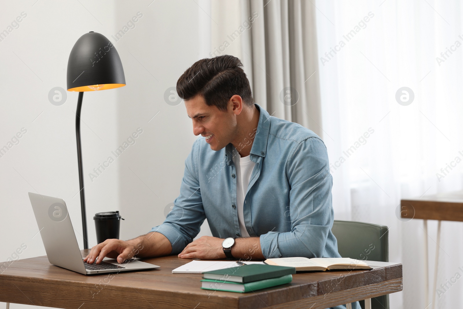 Photo of Man with laptop studying at table in library