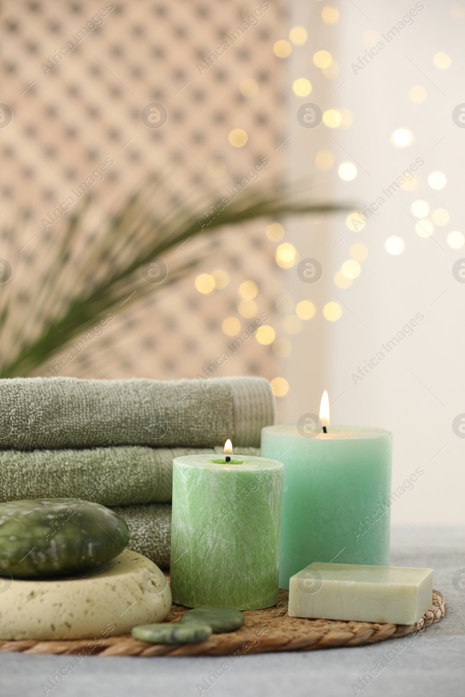 Photo of Spa composition. Burning candles, stones, soap and towels on grey table