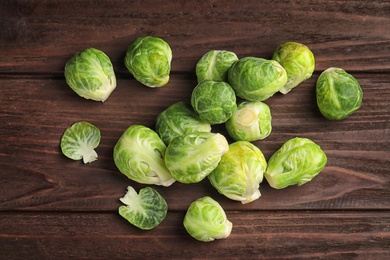 Fresh Brussels sprouts on brown wooden table, flat lay