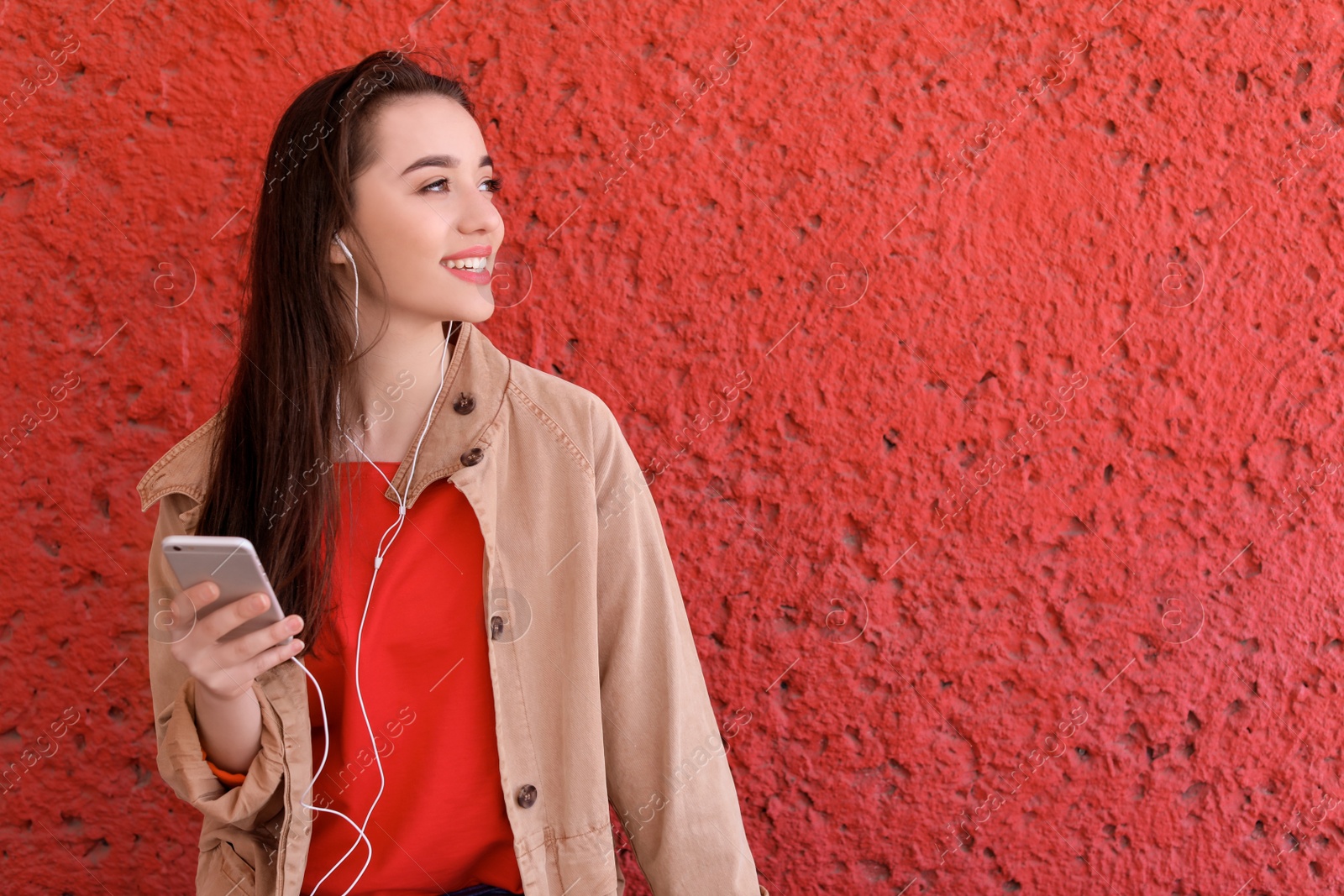 Photo of Young woman using phone for listening to music on color background