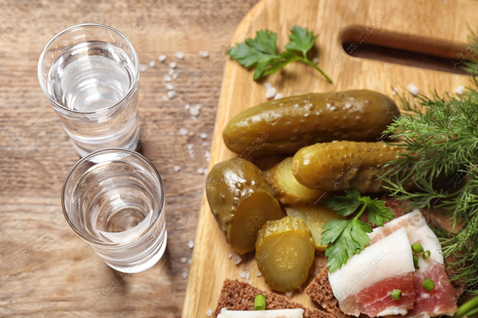 Photo of Cold Russian vodka with snacks on wooden table, above view