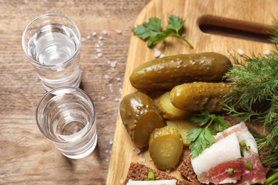 Photo of Cold Russian vodka with snacks on wooden table, above view