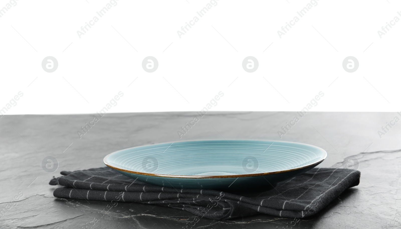 Photo of Empty blue plate and napkin on black slate table against white background