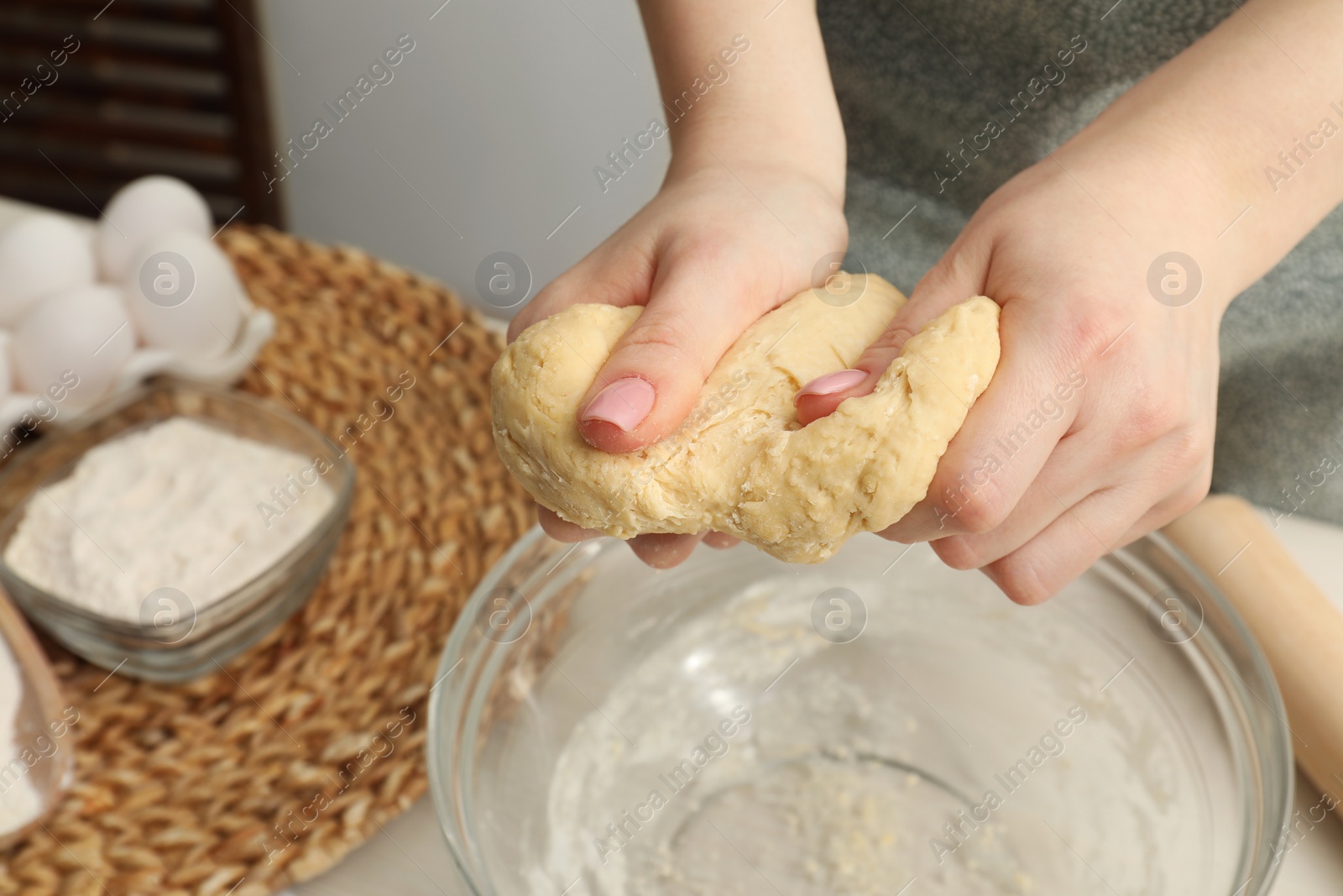 Photo of Woman kneading raw dough at table, closeup