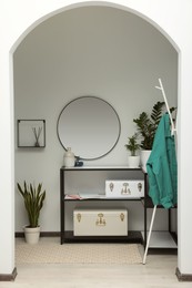 Stylish hallway interior with round mirror and rack