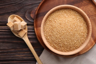 Photo of Bowl and spoon with brown sugar on wooden table, flat lay