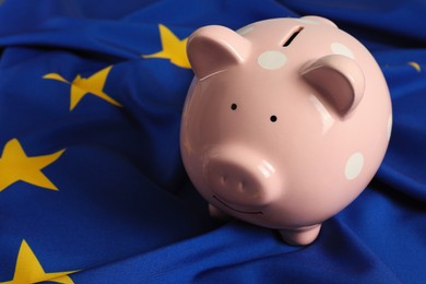Photo of Pink piggy bank on European Union flag, closeup