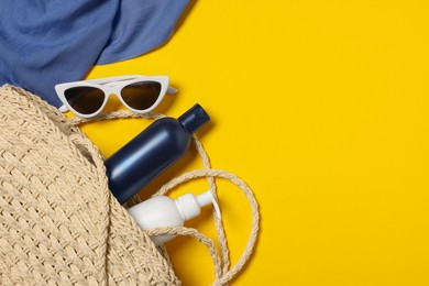 Flat lay composition with wicker bag and other beach accessories on yellow background. Space for text