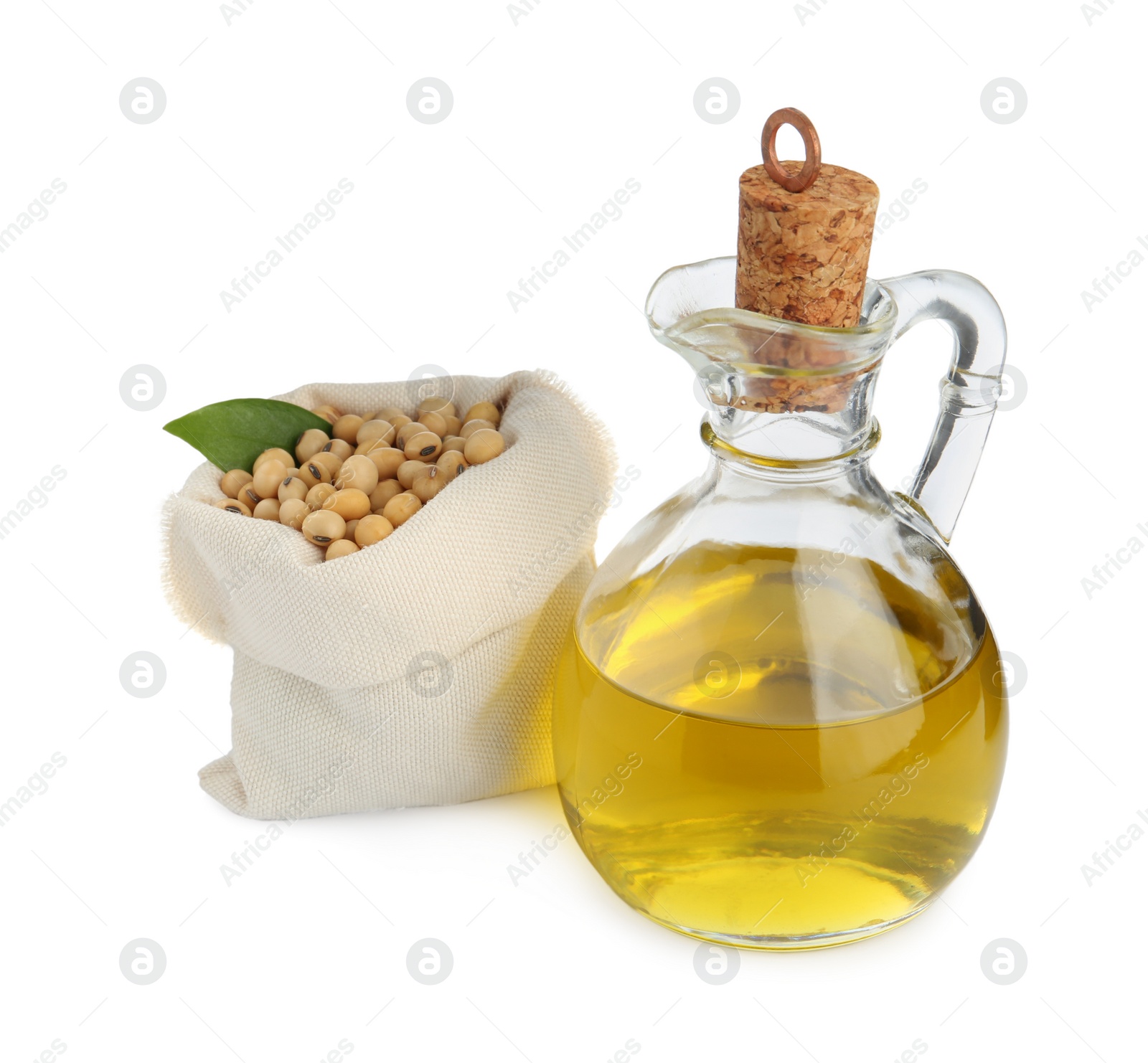 Photo of Glass jug of oil and soybeans on white background