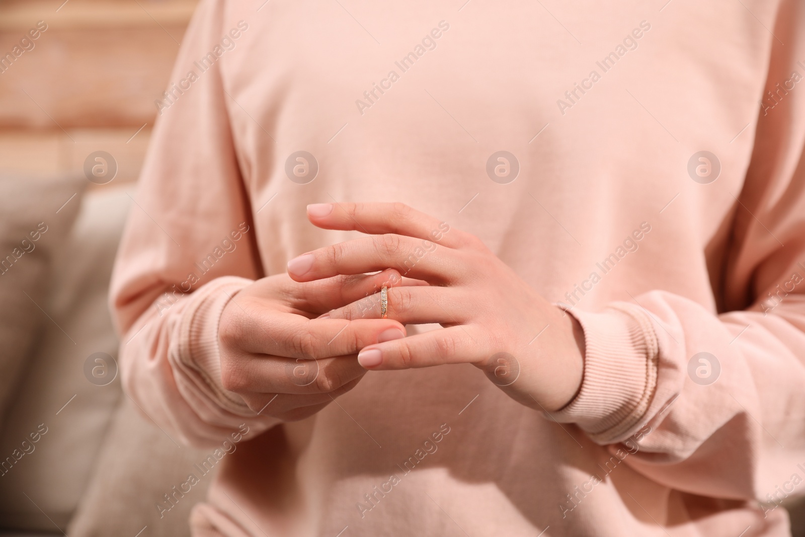 Photo of Woman taking off wedding ring indoors, closeup. Divorce concept