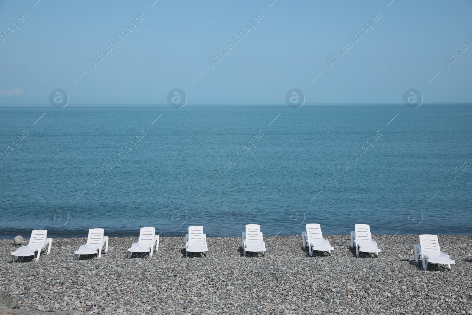 Photo of Beautiful view of sunbeds on pebble beach near sea