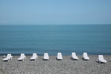 Beautiful view of sunbeds on pebble beach near sea