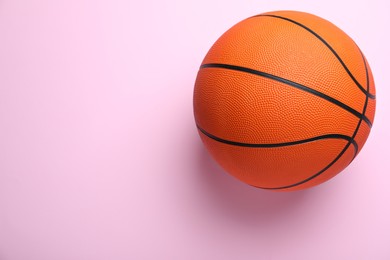 Orange ball on pink background, top view with space for text. Basketball equipment